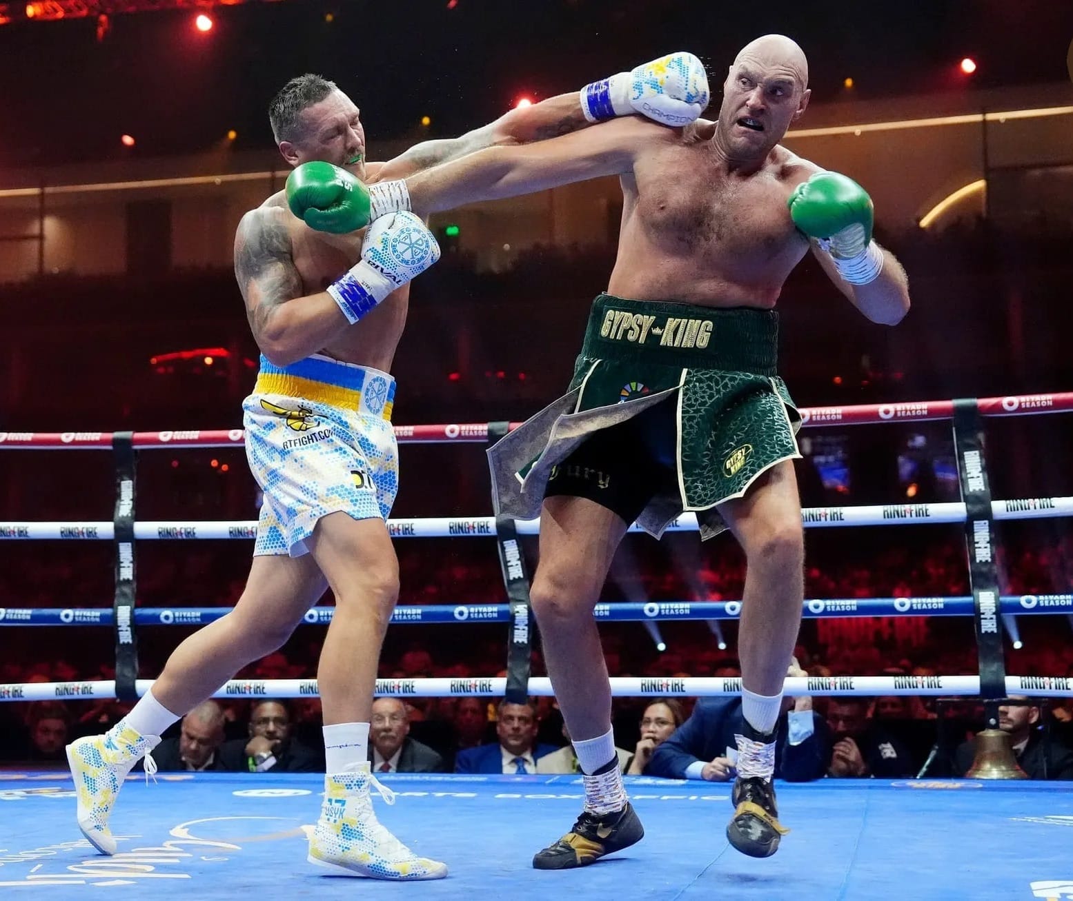 Fury with his left foot off the ground has landed a right jab and was captured in a silly pose, his expression is fearful as Usyk - in a textbook southpaw stance - throws a left straight over the top. Fury's shorts say "GYPSY KING", Usyk's gloves say "CHAMPION".