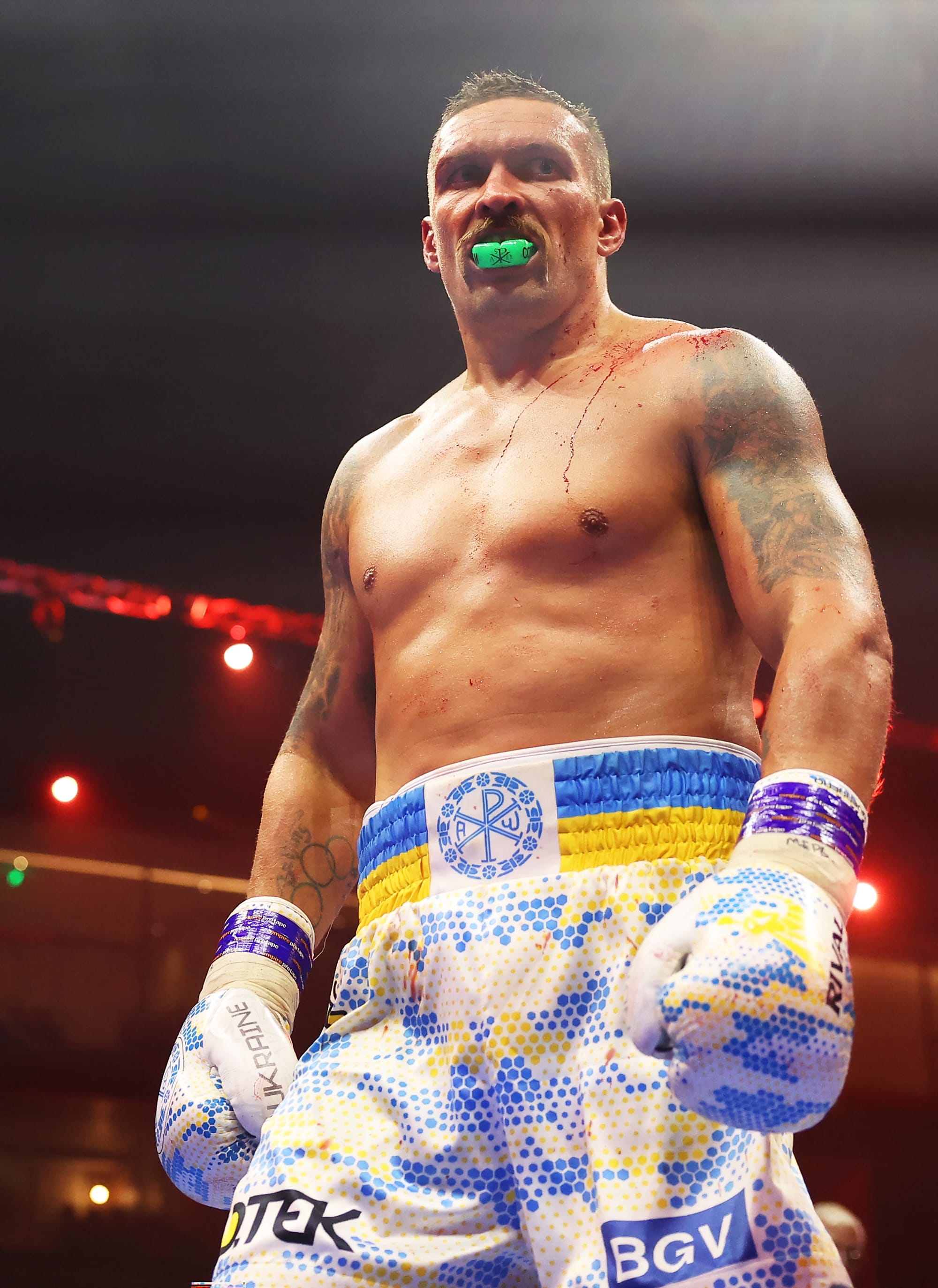 Usyk stands over the camera, eyes fixed elsewhere, with his arms cocked by his side. His trunks and gloves bear the colours of the Ukranian flag. His left shoulder is covered in blood. Fury's blood.