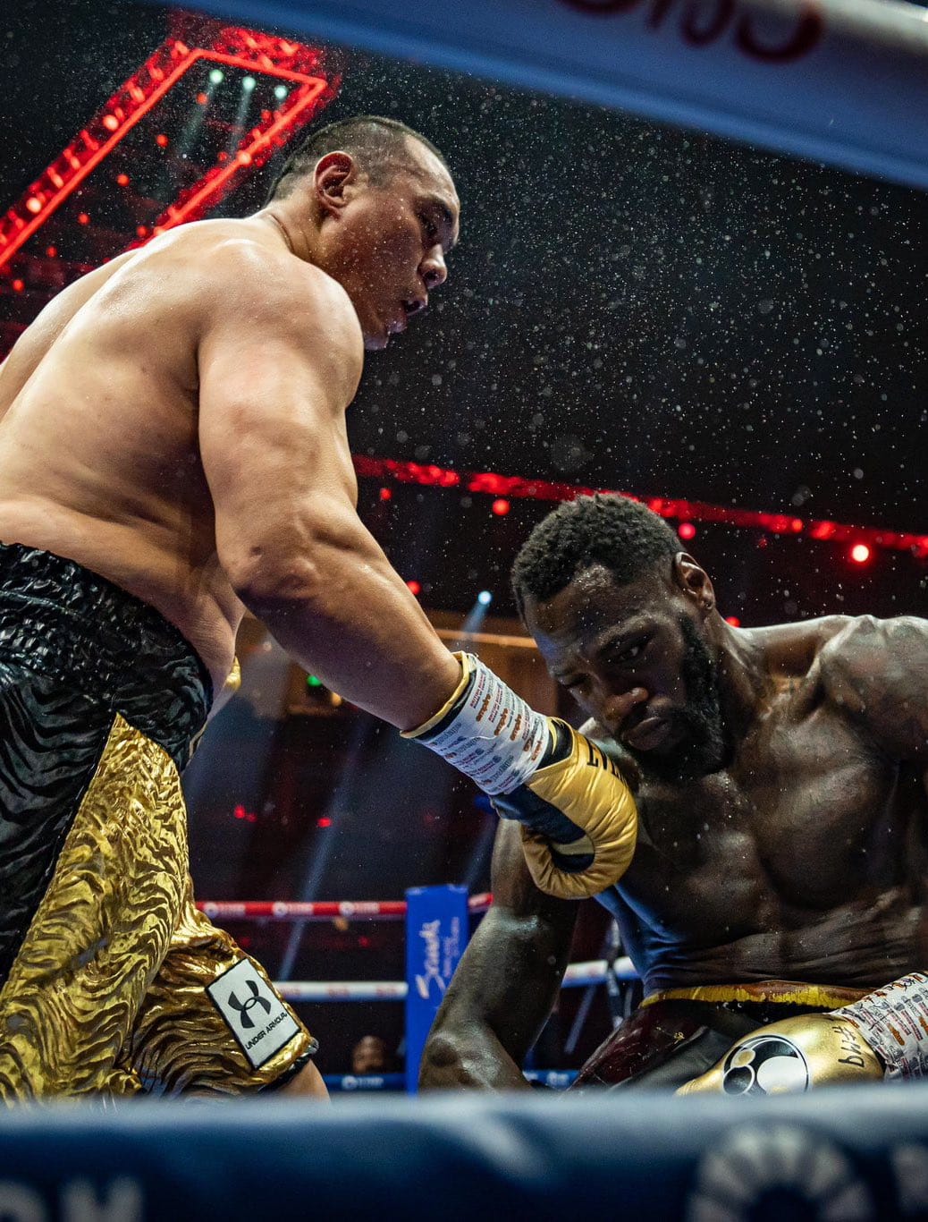 Wilder less than a second after Zhang's knockout punch landed. Beads of sweat are flying everywhere and are illuminated by the ring lights. Wilder has one eye asleep and one completely glazed over as he's halfway to the ground as Zhang towers over him open-mouthed. Zhang's trunks have such a prominent Under Armour logo that my friend asked if this photo was an ad.