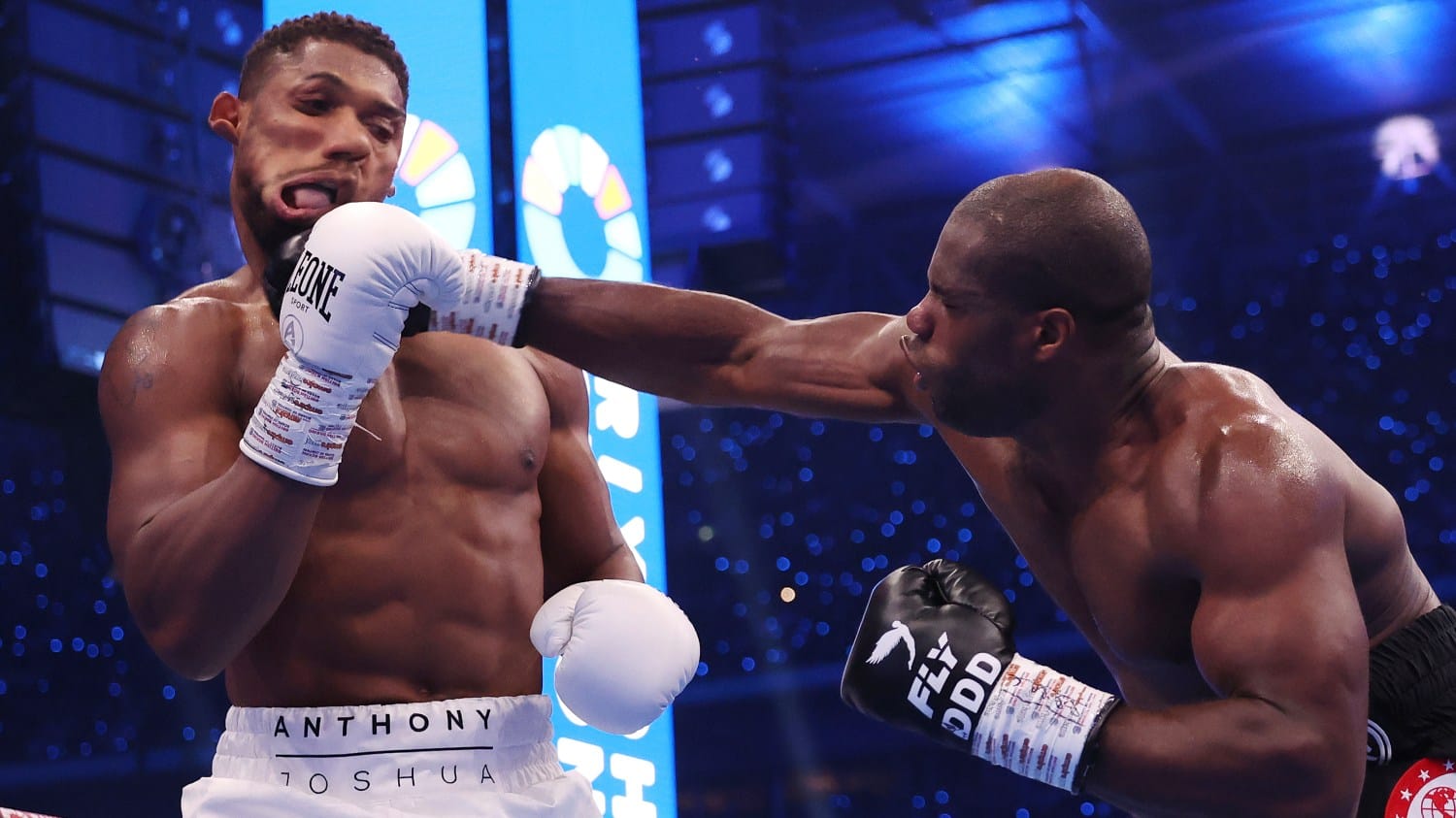 Daniel Dubois landing a wild right hand on Anthony Joshua to knock him down at the end of the first round, Joshua's face is graphically contorted by the impact