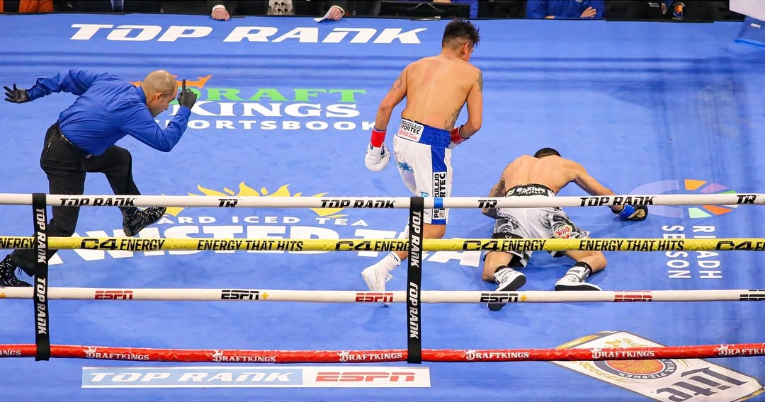 Oscar Valdez lying down on the canvas after getting knocked down by Emmanuel Navarrete, the referee looks very funny as he runs in to start the count