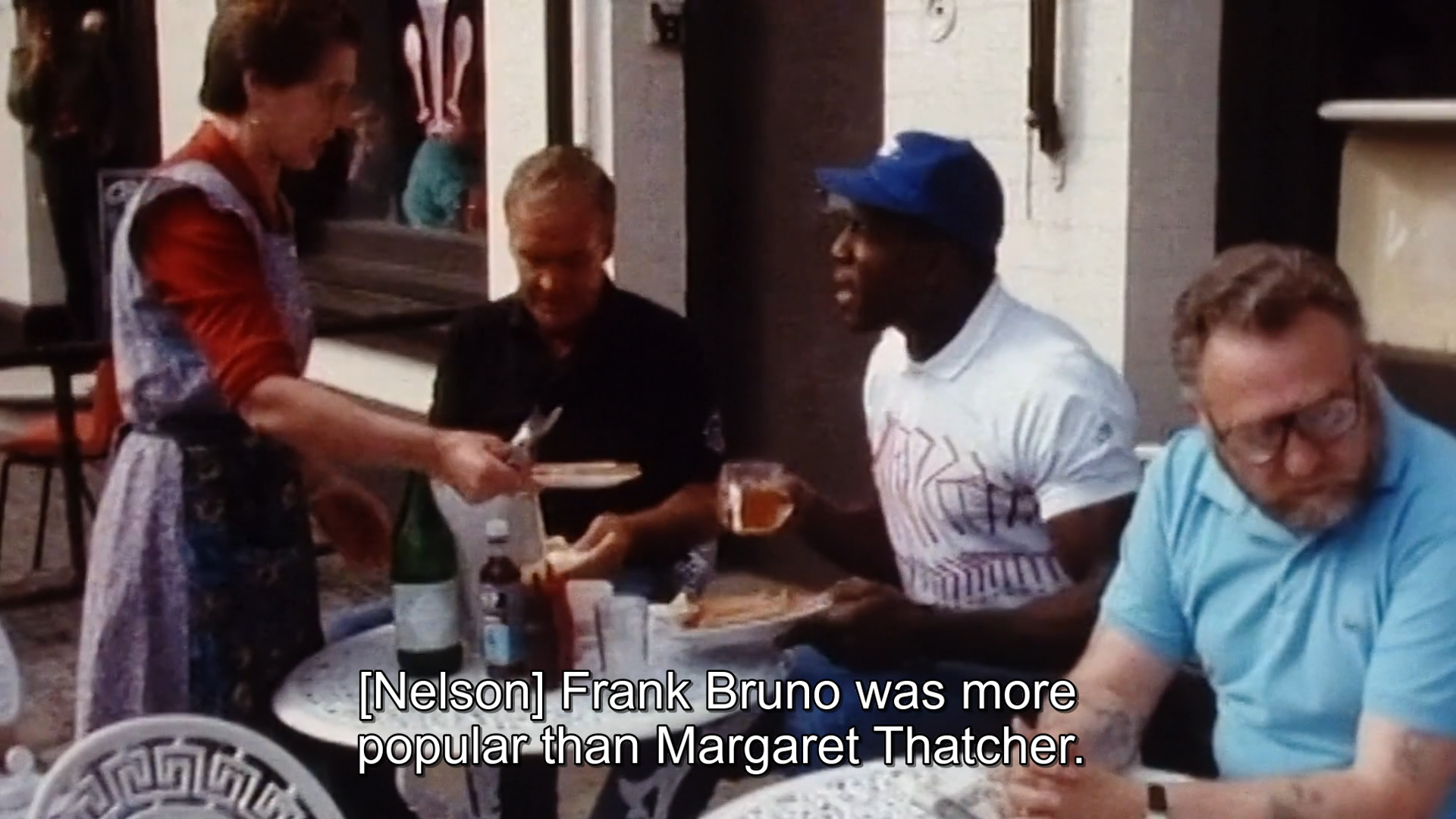 A screenshot of Frank Bruno getting breakfast at a cafe in the late 80s, the subtitles say "Frank Bruno was more popular than Margaret Thatcher"